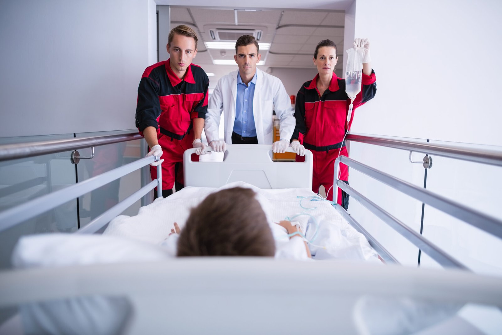 Doctors pushing emergency stretcher bed in corridor at hospital